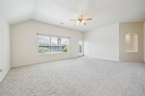 an empty room with windows and ceiling fan