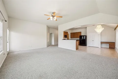 a view of a livingroom with a ceiling fan a kitchen space with wooden floor and a ceiling fan