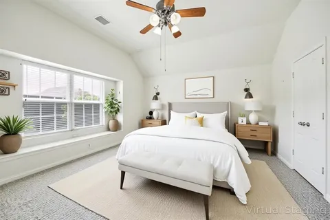 a bedroom with a large bed and a chandelier fan