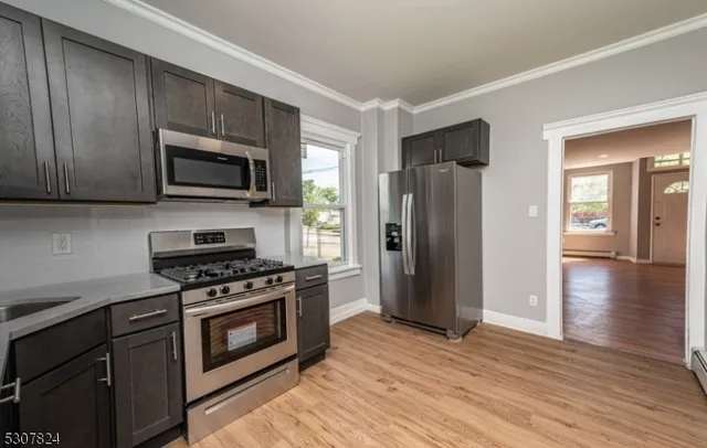 a kitchen with stainless steel appliances a stove a microwave and a hard wood floors