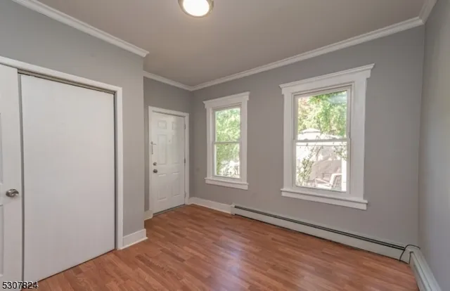 a view of an empty room with wooden floor and window