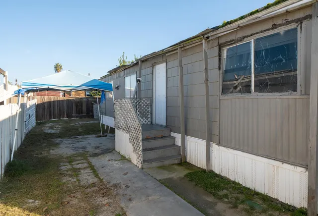 a view of a house with a small yard and wooden floor and fence