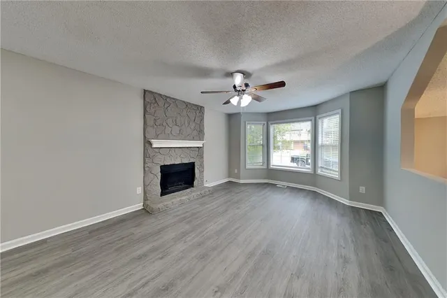a view of an empty room with wooden floor fireplace and a window