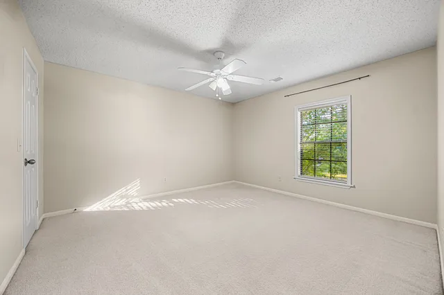 an empty room with a window and a ceiling fan