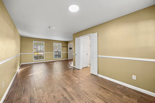 an empty room with wooden floor and windows