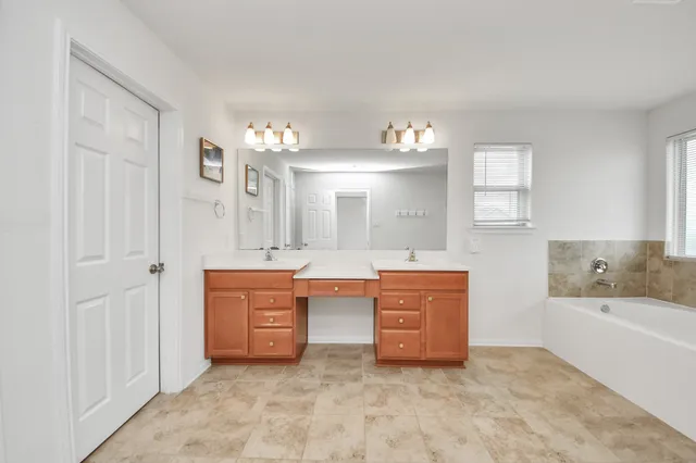 a spacious bathroom with a tub sink and mirror