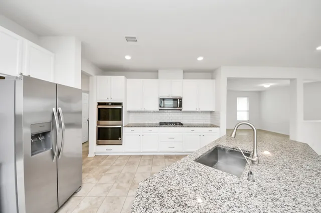 a kitchen with stainless steel appliances granite countertop a sink refrigerator and microwave