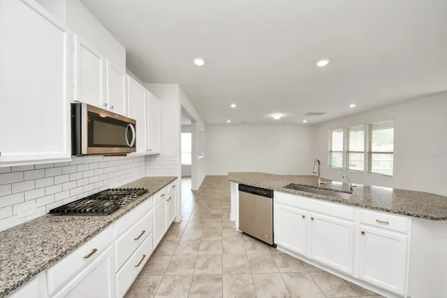a kitchen with stainless steel appliances granite countertop a sink stove and cabinets