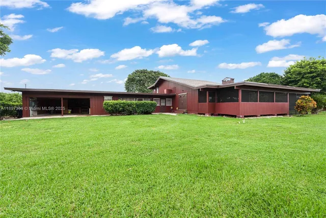 a view of a house next to a big yard and large trees