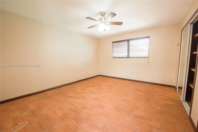 an empty room with closet and a ceiling fan