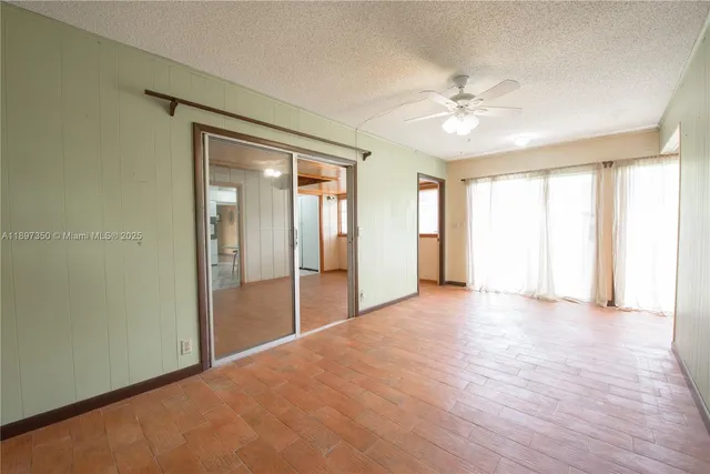 a view of an empty room with wooden floor and a kitchen