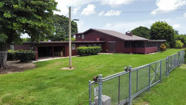 an aerial view of a house with swimming pool garden and tall trees
