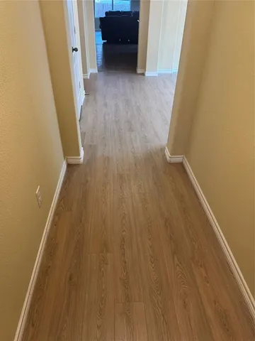 a view of a hallway to rooms and wooden floor