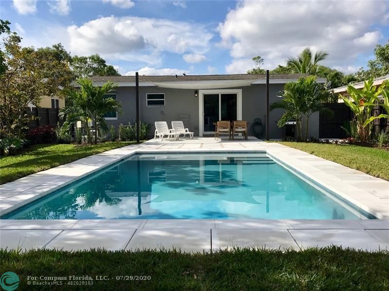 Private saltwater, heated pool with sun shelf, modern concrete pavers, lush landscaping and privacy fence.