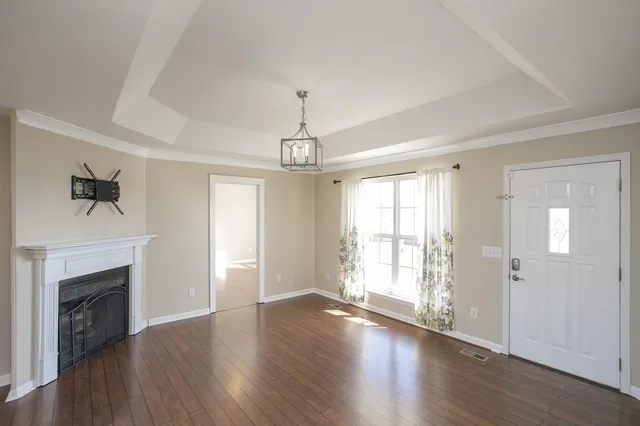 a view of an empty room with wooden floor fireplace and a window
