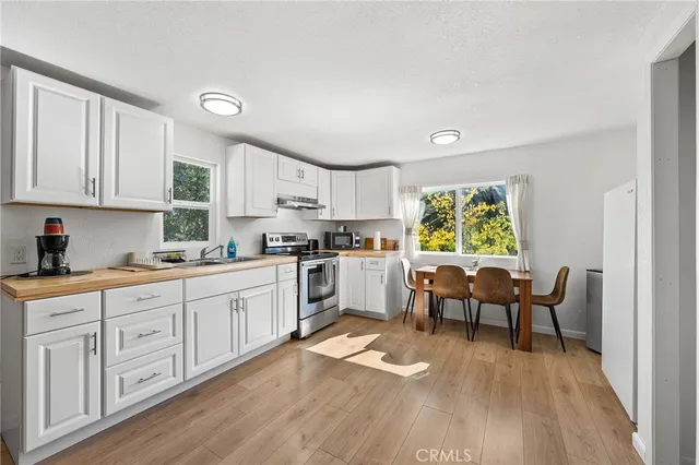 a kitchen with granite countertop a stove a sink a dining table and chairs