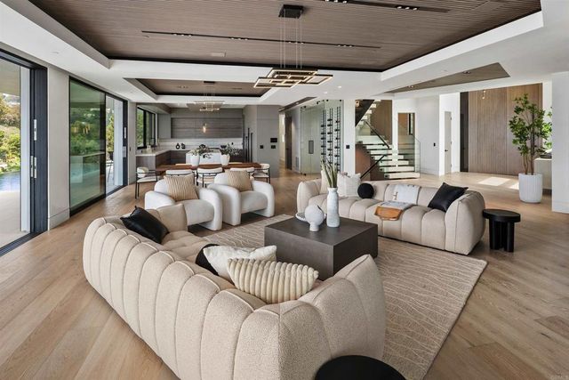 a living room with couches floor to ceiling window and a flat screen tv