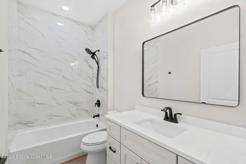a bathroom with a granite countertop sink a toilet and a bathtub