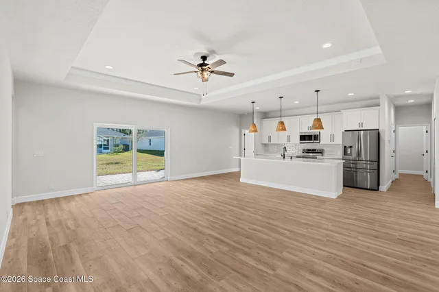 a view of kitchen with stainless steel appliances granite countertop a stove top oven a refrigerator a sink dishwasher with a dining table and chairs with wooden floor
