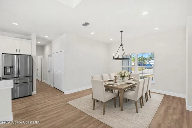 a dining room with furniture a chandelier and wooden floor