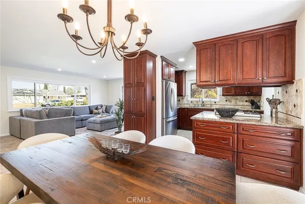 a kitchen with stainless steel appliances granite countertop a refrigerator a sink dishwasher a stove and a dining table with wooden floor