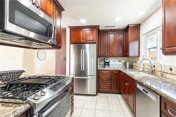 a kitchen with stainless steel appliances granite countertop a stove a sink dishwasher a refrigerator and cabinets with wooden floor