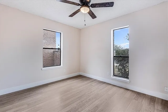 a view of an empty room with a window and wooden floor