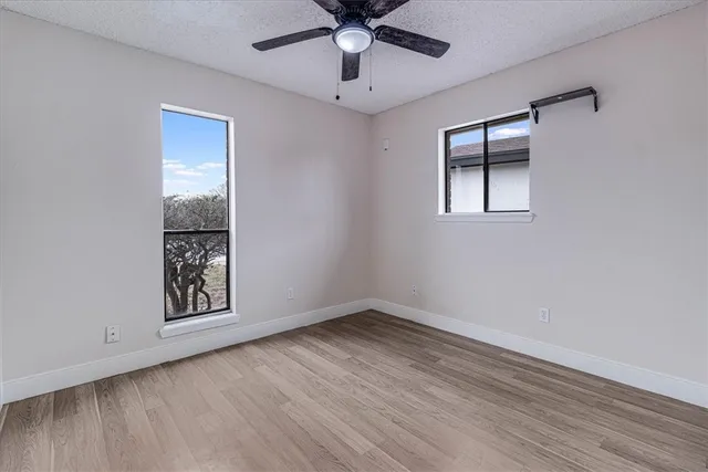 a view of an empty room with window and wooden floor