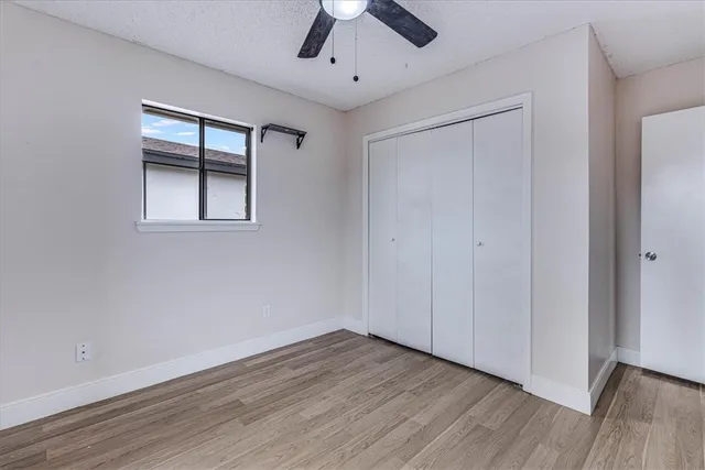 a view of empty room with wooden floor and fan