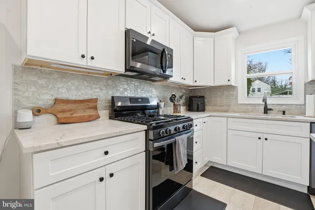 a kitchen with stainless steel appliances granite countertop white cabinets sink and stove