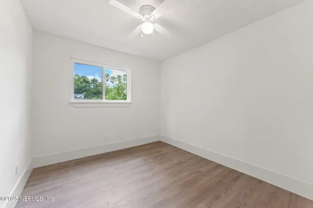 an empty room with windows and fan