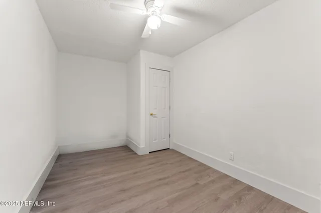 an empty room with wooden floor and fan