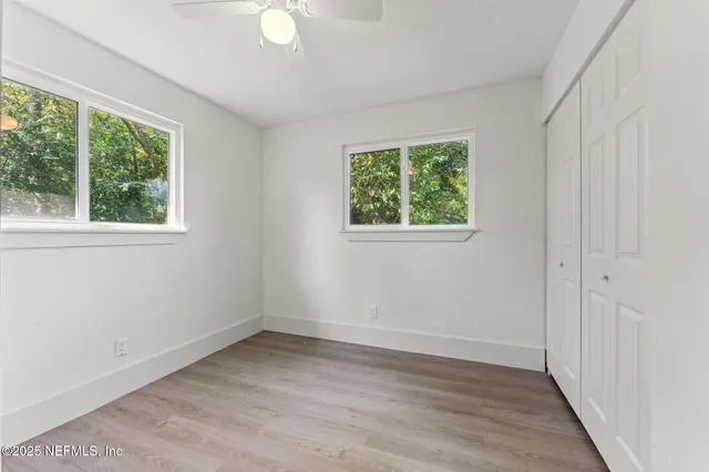 an empty room with wooden floor and windows