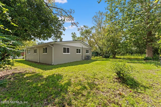 a view of a house with backyard and trees