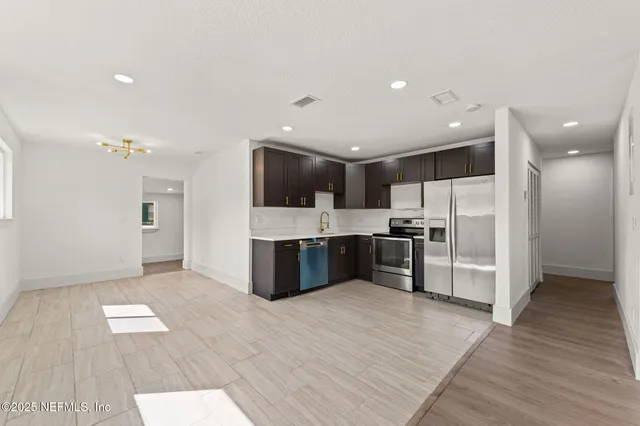 a large kitchen with stainless steel appliances kitchen island a large counter top and a refrigerator
