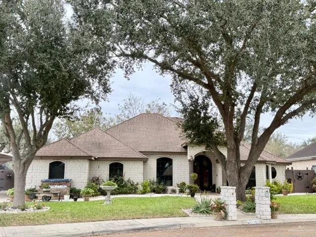 a front view of a house with garden and trees