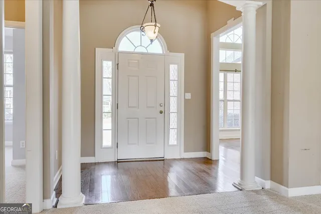 an empty room with wooden floor windows and entryway