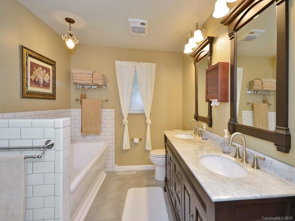 43 Cold Springs Road Hendersonville, NC 28792 - Photo 14 of 24 a bathroom with a granite countertop sink a mirror a vanity and a shower