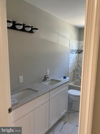a bathroom with a granite countertop sink a toilet and a shower