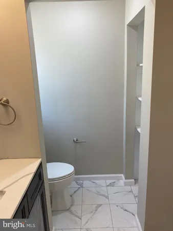 a bathroom with a granite countertop toilet and sink