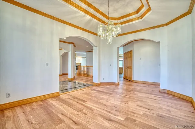 a view of a hallway with wooden floor and a chandelier