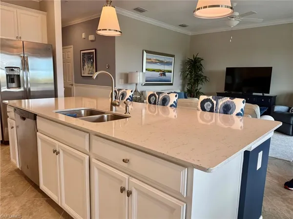 a kitchen with kitchen island a sink appliances and a living room