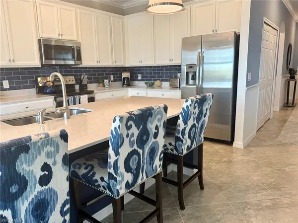 a kitchen with stainless steel appliances granite countertop a table chairs and a refrigerator