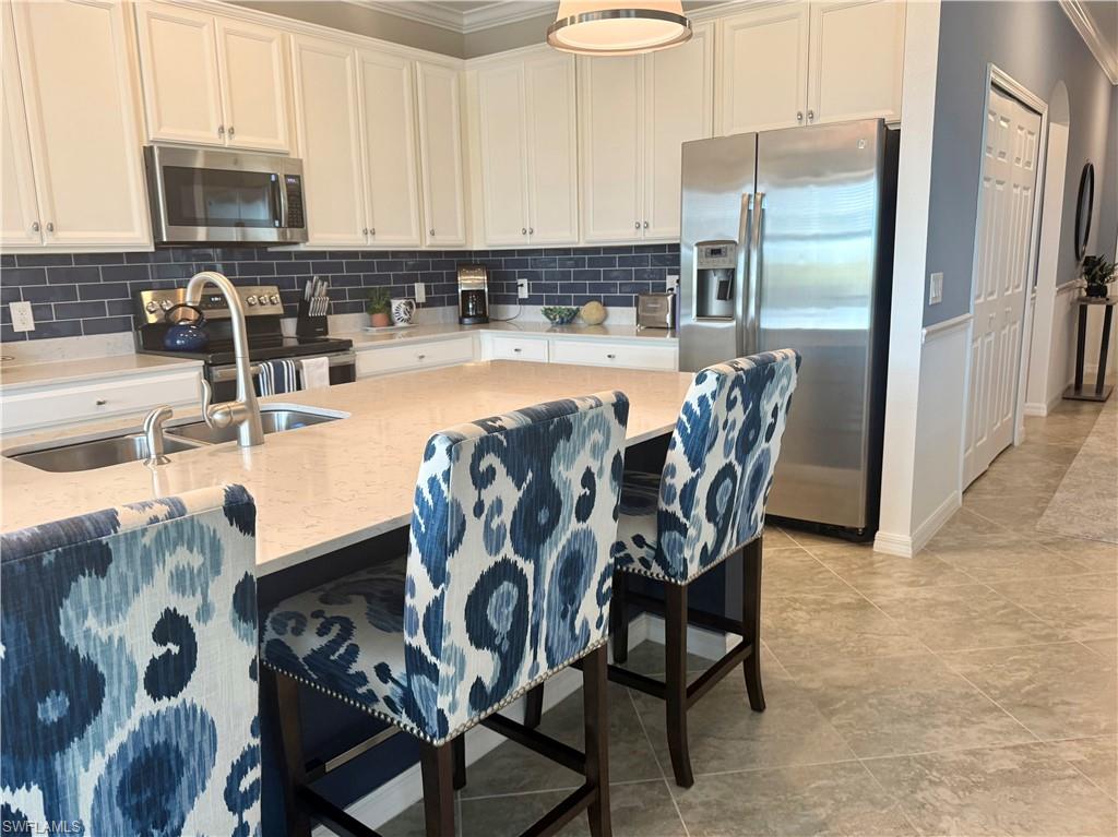 9584 Trevi Court, Unit 5242 Naples, FL 34113 - Photo 15 of 50 a kitchen with stainless steel appliances granite countertop a table chairs and a refrigerator