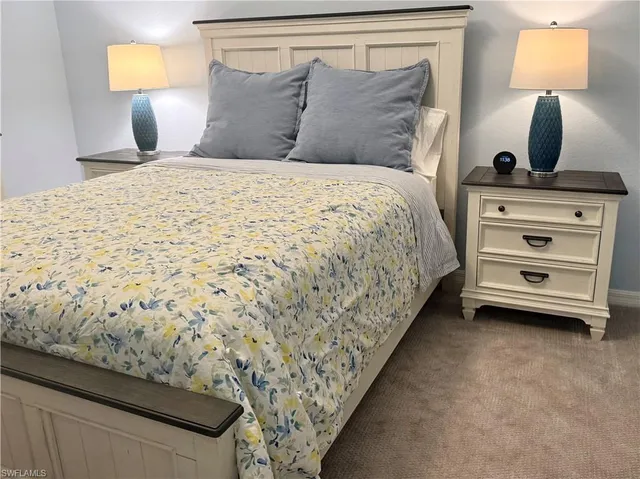 a bedroom with a bed and a lamp on dresser