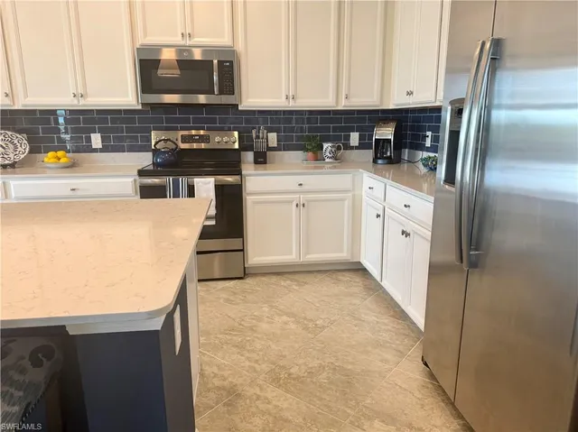 a kitchen with stainless steel appliances a refrigerator sink and white cabinets