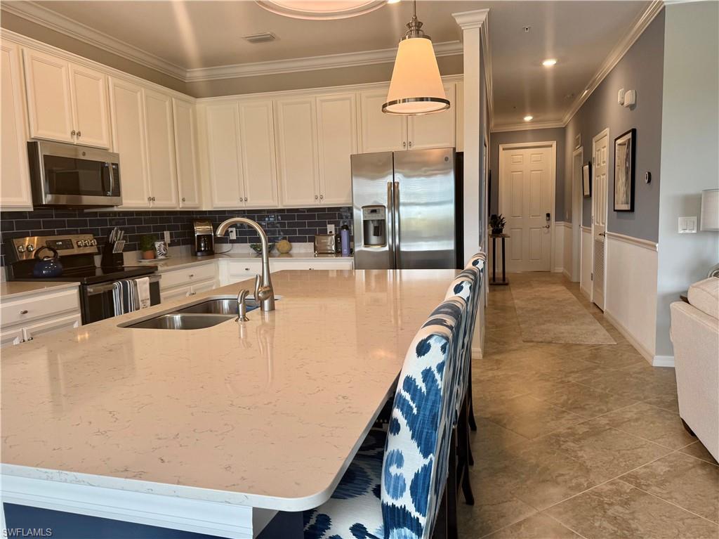 9584 Trevi Court, Unit 5242 Naples, FL 34113 - Photo 7 of 50 a kitchen with stainless steel appliances granite countertop a refrigerator a stove and a sink with wooden floor