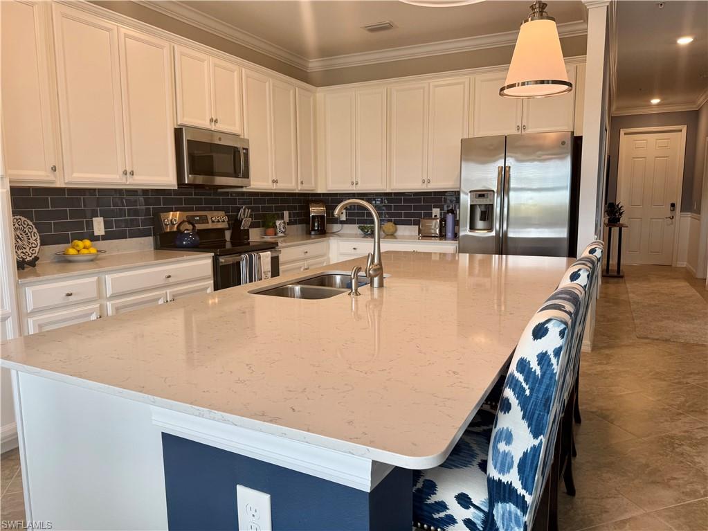 9584 Trevi Court, Unit 5242 Naples, FL 34113 - Photo 8 of 50 a kitchen with stainless steel appliances a stove a refrigerator a sink a stove and white cabinets with wooden floor