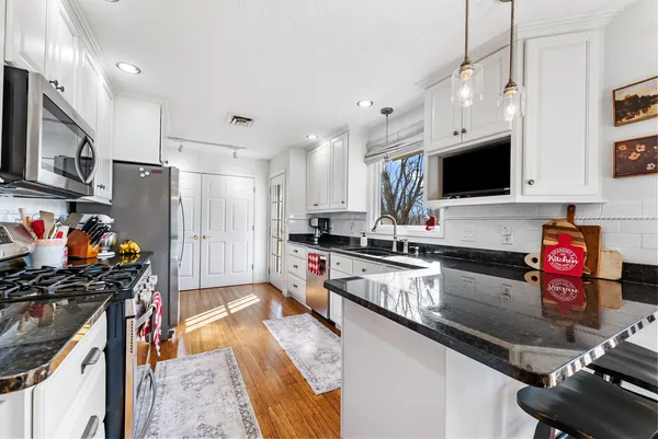 a kitchen that has a lot of cabinets a sink and appliances