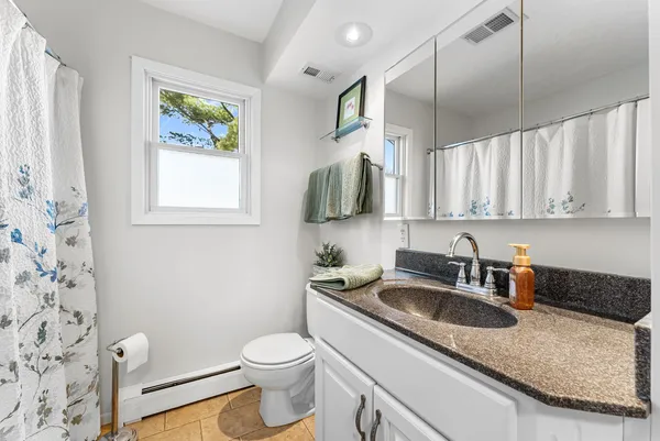 a close view of two sink and a toilet next to a window